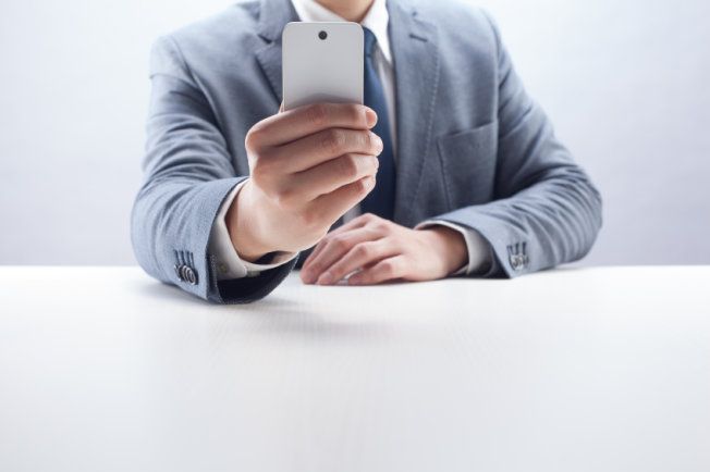 Stock image of a man in a suit using a camera phone.