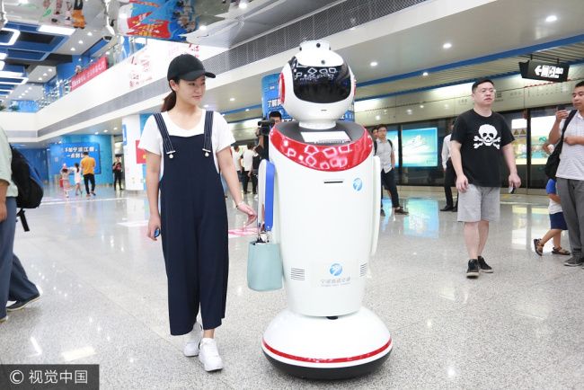 A smart robot helps a passenger carry a handbag at Ningbo Railway Station in Zhejiang Province, on August 7, 2017. The smart robot has been activated to help passengers search for ticket fares, print route maps and carry their luggage. [Photo: VCG]